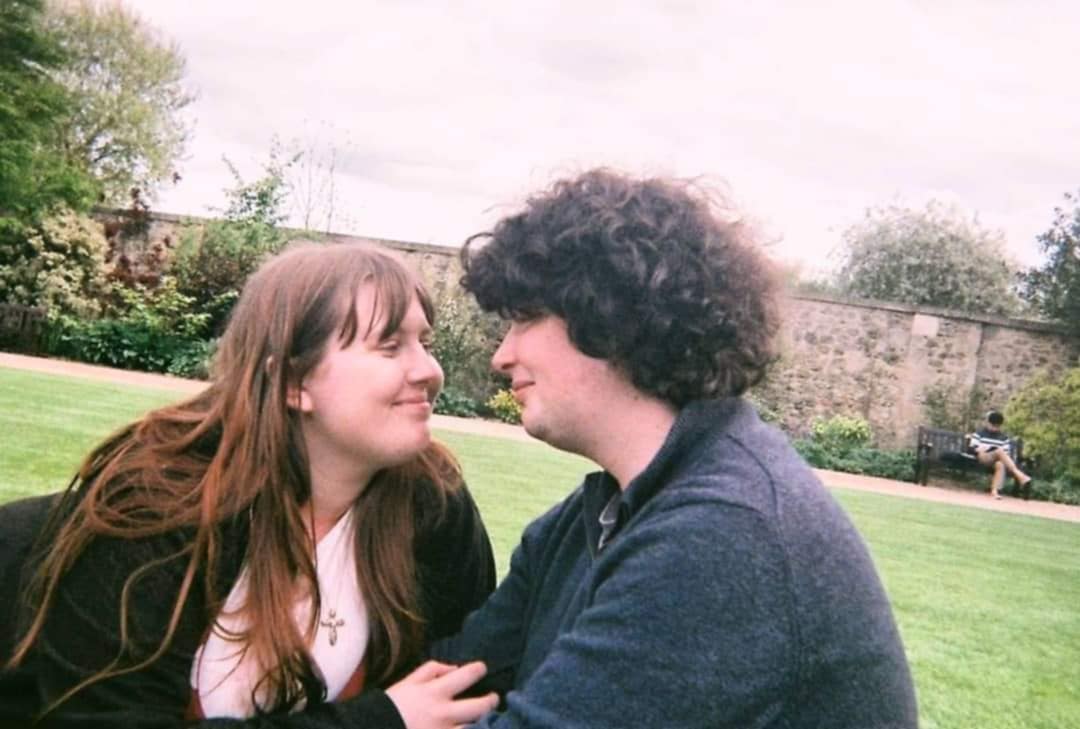 Finn and Rhianna sitting in a walled garden looking at each other